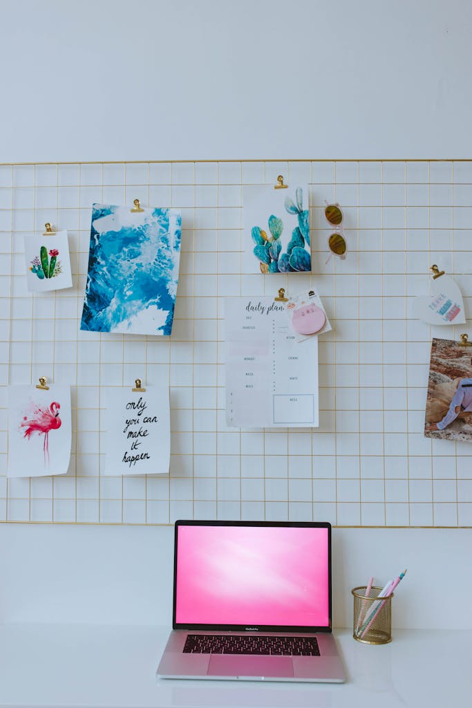A tidy workspace with a laptop and an inspiring moodboard against a grid wall.