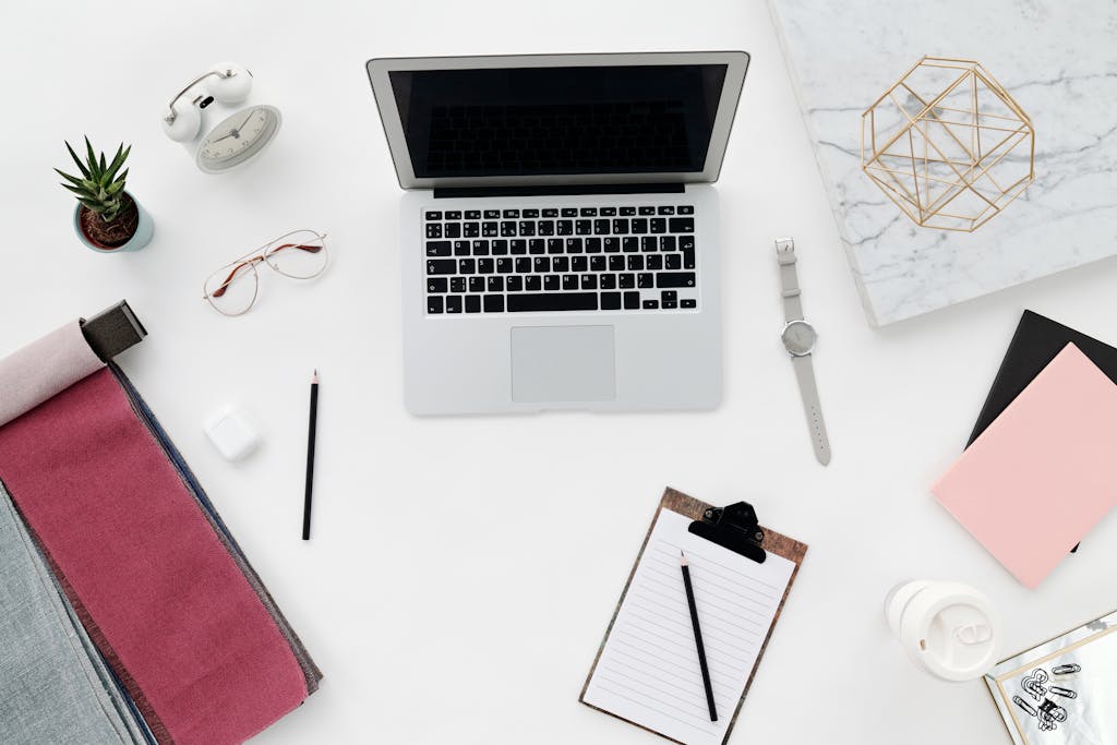 Neat and modern workspace flat lay with a laptop, office supplies, and a plant for inspiration.