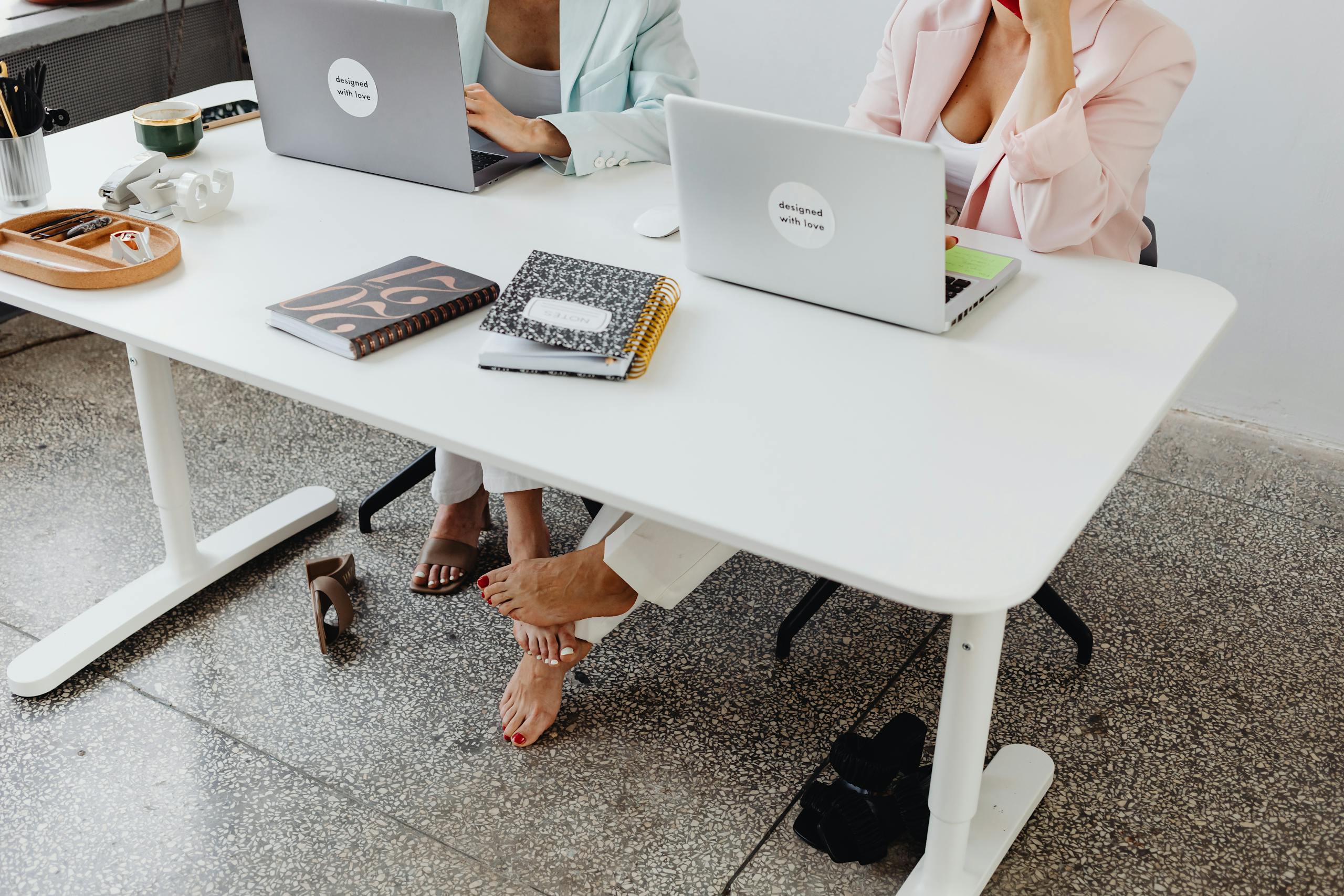 Two women collaborate in a modern office setting, showcasing teamwork and connection.