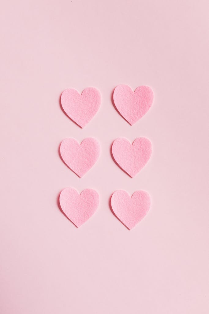 Soft pink heart shapes on a light pink background, perfect for romantic themes.